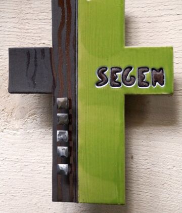 Ein Kreuz in zwei Farben: linke Seite: holzbraun, rechte Seite grasgrün, auf der rechten Seite steht das Wort "Segen". Foto: Martha Gahbauer, pfarrbriefservice.de